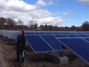 Jenny Isler stands in front of solar panels at SolarFlair